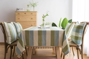 Detail shot of striped cotton linen tablecloth featuring decorative beige tassels on edges