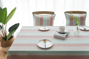 Detail of striped waterproof tablecloth with matching chair cushions in mint and pink