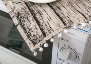 Détail de la housse de micro-ondes en coton lin motif bois avec franges pompons