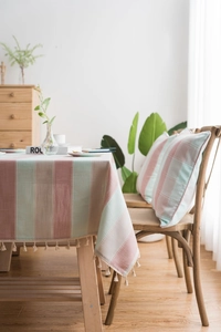Detailed macro view of striped linen tablecloth with decorative cream tassel fringe edge