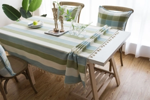 Detail shot of green and blue striped tablecloth with delicate tassel trim and soft texture