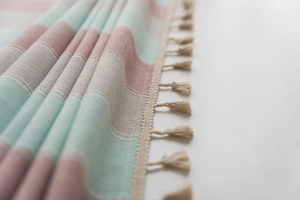 Detail shot of striped Nordic style throw blanket with decorative beige tassels