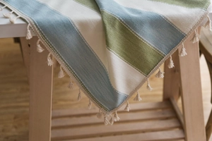 Detail of striped linen tablecloth showing green and blue weave with elegant fringe tassels