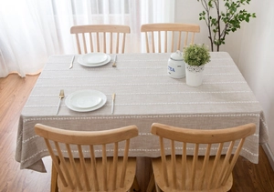 Close-up of beige linen-textured tablecloth featuring white linear geometric embroidery