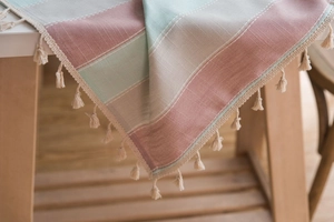 Close-up of striped cotton linen tablecloth with sage green colors and fringe trim