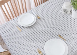 Detailed close-up of beige cotton linen plaid tablecloth with grey grid pattern on wood table