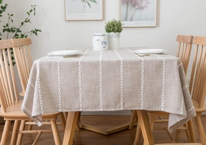 Detail of embroidered vertical stripes on beige cotton linen tablecloth with leaf patterns