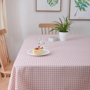 Detail van roze geruit tafelkleed op houten tafel met decoratie en groene planten