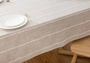 Macro detail of textured linen tablecloth with elegant white vertical stripe embroidery