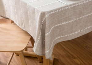 Detail of linen cotton tablecloth with white leaf embroidery on oat neutral fabric