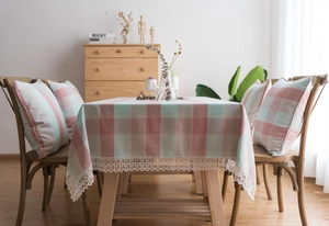 Close-up of green and pink checkered tablecloth with scalloped lace edges on a wooden table