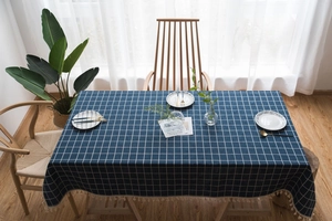 Close-up of deep blue checkered cotton linen tablecloth with creamy white tassel details
