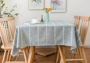 Close-up of a Nordic-style sage green tablecloth with white leaf pattern on a wood table
