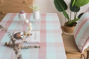 Close-up of green and pink checkered tablecloth with matching cushion in a cozy setting