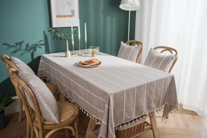 Detailed close-up of linen tablecloth with white embroidery stripes and handmade tassels