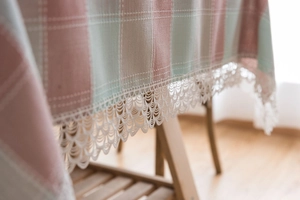 Macro view of green and pink checkered tablecloth with elegant white lace embroidery