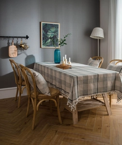 Close-up of grey plaid tablecloth with elegant white fringe tassels and matching cushions