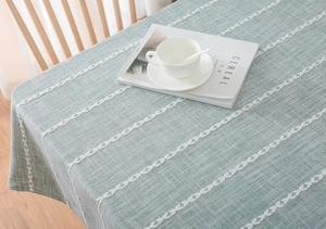 Close-up of light green cotton linen tablecloth with white leaf embroidery texture