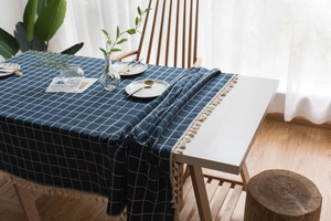 Detail of navy blue plaid tablecloth with beige tassels on a cotton linen fabric