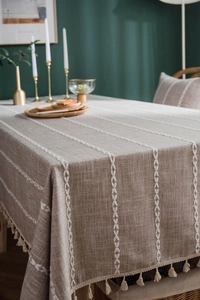 Detail of coffee linen tablecloth featuring white embroidery lines and elegant tassels