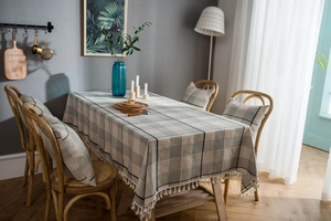 Close-up of gray checkered cotton linen tablecloth with white tassel ball fringe details