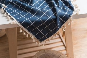 Close-up of deep blue checkered tablecloth with cotton linen texture and cream tassels