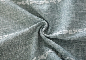 Macro shot of green linen fabric texture with white leaf embroidery and soft folds