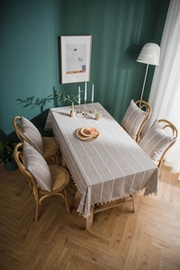 Detail of greyish brown linen tablecloth with white stripes and handmade tassel edge