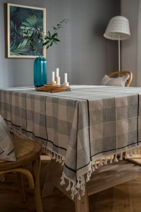 Detailed view of gray checkered cotton linen tablecloth with elegant white fringe tassels