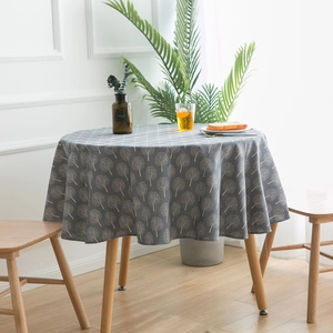Modern grey round linen tablecloth with white tree prints on a wooden dining table