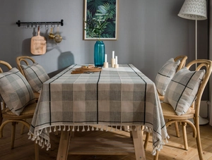 Detail of grey plaid cotton linen tablecloth with white tassel edge and matching chair cushion