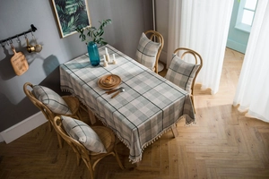 Close-up of gray checkered cotton linen tablecloth with elegant white fringe tassels