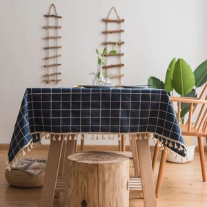Navy blue checkered cotton linen tablecloth with beige tassels in a cozy dining room