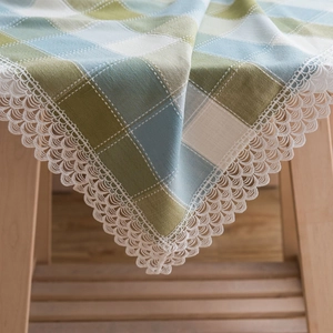 Green and blue plaid tablecloth with decorative white lace edges in a rustic farm style