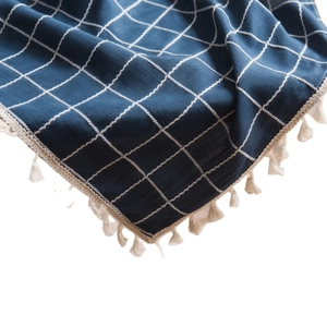 Navy blue checkered cotton linen tablecloth with ivory tassels shown from a side angle