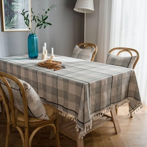 Gray checkered cotton linen tablecloth with tassel edges on a wooden dining table