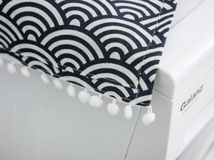 Detail of navy Japanese wave pattern dust cover with white pom-pom fringe and cotton canvas