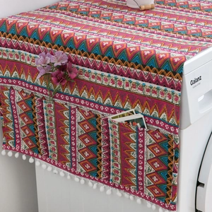 Detail of red Bohemian fridge cover showing side storage pockets and white pom-pom trim