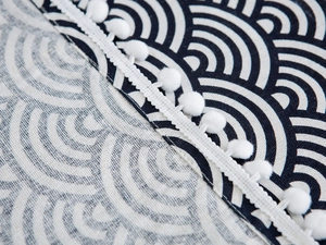 Close-up of Seigaiha wave pattern fabric with white pom-pom trim and linen texture
