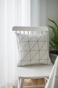 Detail of modern black and white geometric pattern pillow on a white wooden chair