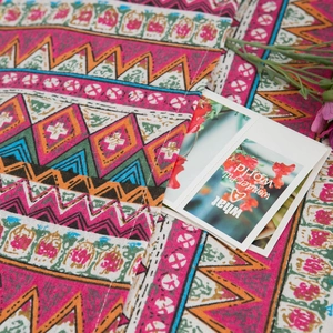 Detail of bohemian red floral pattern fabric with cotton linen texture and floral card