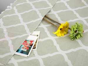 Close-up of geometric quatrefoil pattern on gray-green linen fabric cover
