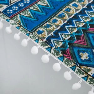 Detailed close-up of Bohemian geometric fabric texture with white pom-pom fringe decor