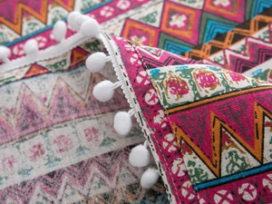 Macro detail of Bohemian geometric print fabric with white pom-pom fringe trim