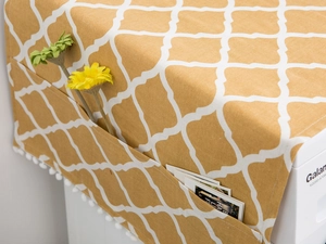 Detail view of mustard yellow geometric dust cover with side storage pockets and pompom trim