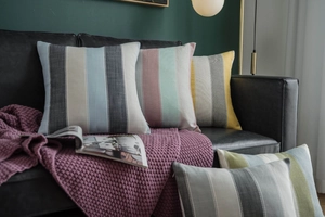 Macro shot of striped pillow covers on a black leather sofa with a Nordic interior style