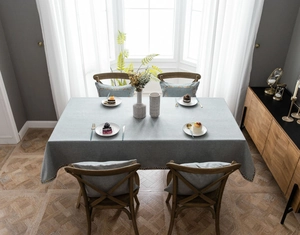 Close-up of grey-blue tablecloth and cushions with bohemian style geometric woven lace