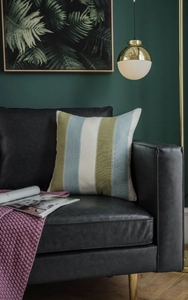 Detail of modern striped cushion cover on black leather sofa in retro living room