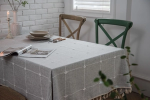 Detail of grey plaid tablecloth featuring 3D accents and elegant beige tassel edges