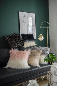 Luxe faux sheepskin plush pillow covers shown in various colors on a black leather sofa